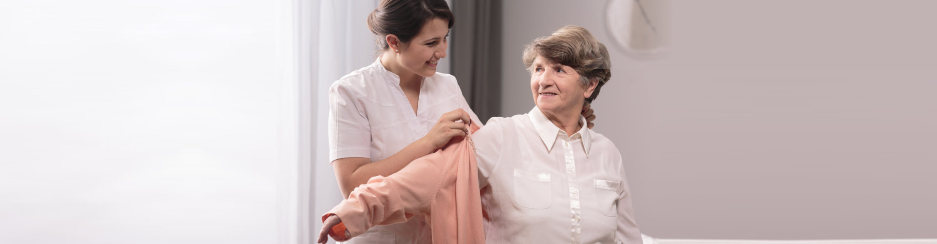 caregiver dressing her senior patient